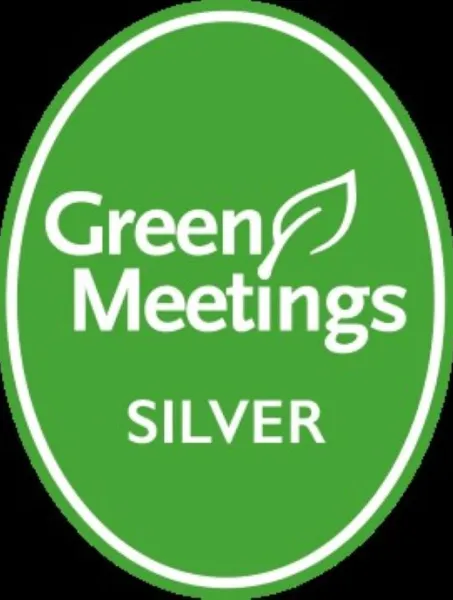 Green oval badge with "Green Meetings" in white, featuring a leaf symbol, and "Silver" below. It conveys a theme of sustainability and achievement.