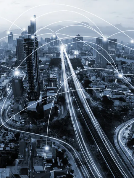 Futuristic city skyline at dusk with glowing interconnected lines above skyscrapers, illustrating a networked, connected technology concept.