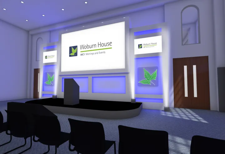 Modern conference room with a podium, large screen displaying "Woburn House," blue-lit walls, row of empty black chairs, and a bright, professional ambiance.