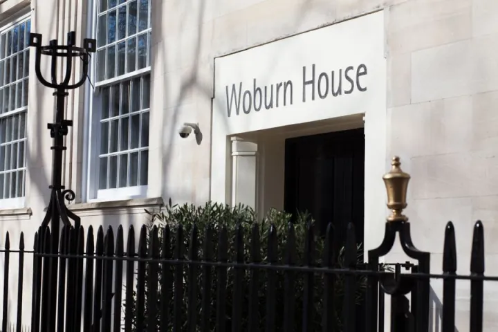 Elegant building entrance labeled "Woburn House." Features large windows, stone facade, and ornate black iron fence, conveying a sense of sophistication.